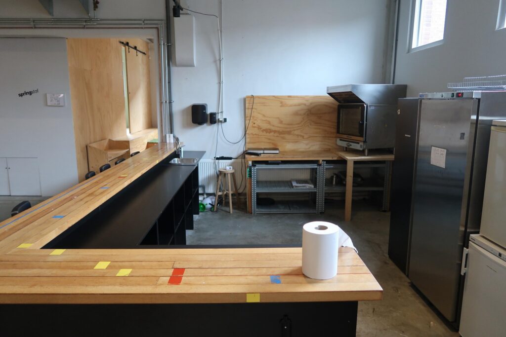Keukenruimte aan het Gedempt Hamerkanaal met houten bar, rvs-apparatuur en een industriële uitstraling.